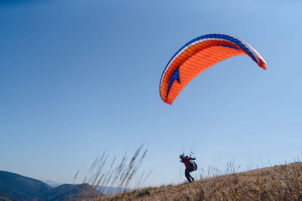 Paraglider landing on the ground against the blue sky.